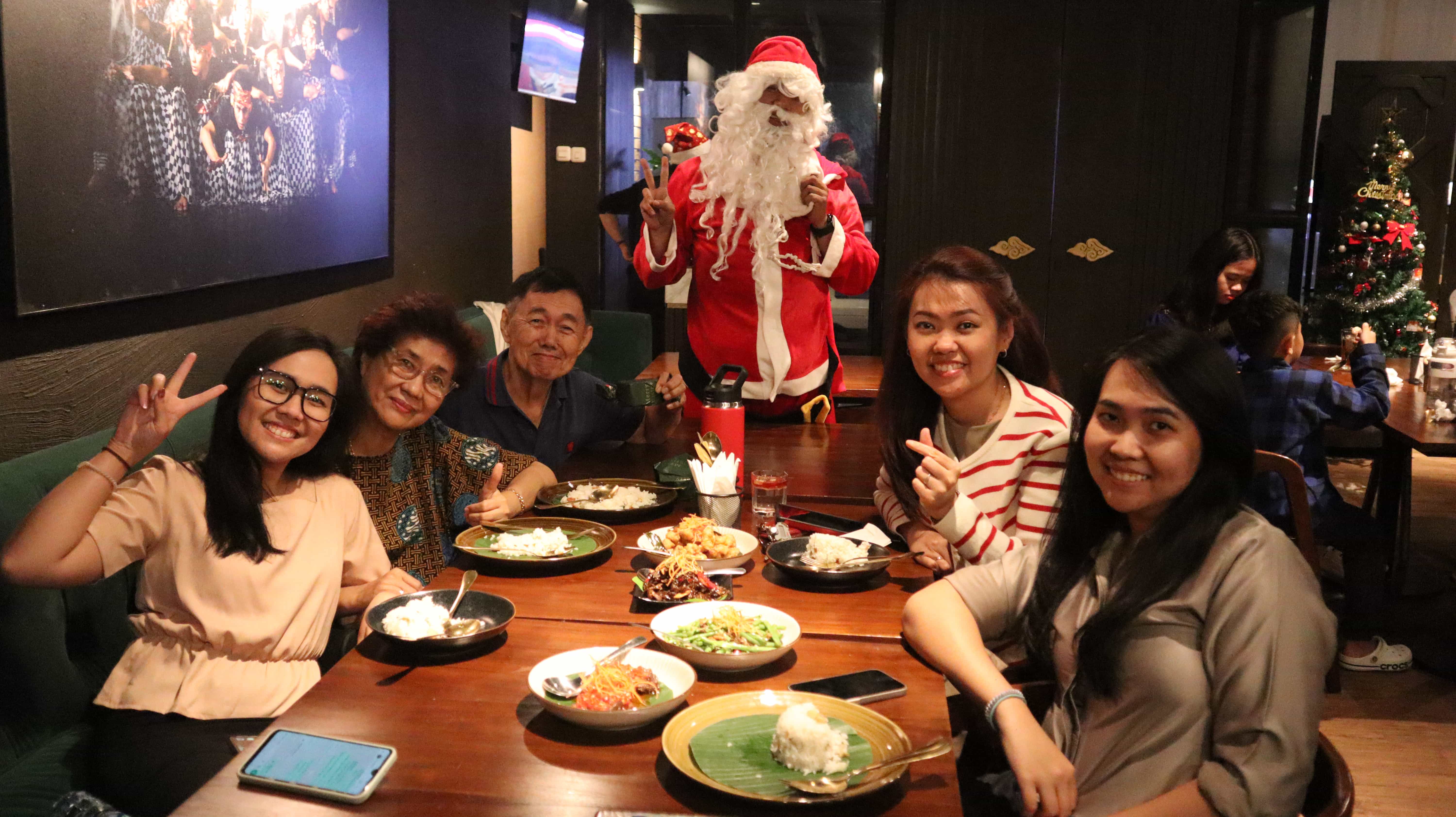 Santa Claus posing with a happy family during Christmas dinner.